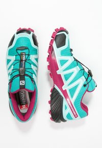 Türkise und rosa Sportschuhe mit strukturiertem Mesh-Obermaterial, schwarzen Akzenten, Schnell-Schnürsystem und gemusterter Gummisohle für Traktion.