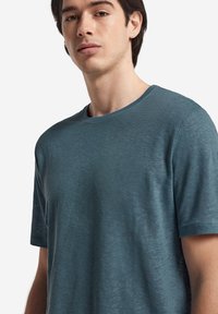 Kortärmad t-shirt med rund halsringning i teal, tillverkad av mjukt, texturerat tyg med en lätt heathered känsla och minimala sömmar.