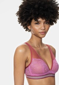 Lingerie bra featuring a soft pink lace overlay with sheer mesh straps and a multi-colored band. V-neck design offers a modern silhouette.