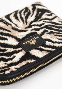 Clutch texturé avec un motif zèbre noir et beige, présentant une bordure en faux cuir noir lisse et une étiquette de logo doré embossé.