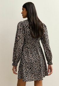 Leopardprint jurk met lange puffmouwen, cinched taille en uitlopende rok, in tinten van zwart en bruin, gemaakt van een lichtgewicht stof.