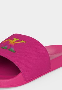 Φανταχτερό ροζ σανδάλι με υφασμάτινο λουρί με πολύχρωμο λογότυπο "CK", ανοιχτή μύτη και διαμορφωμένο πέλμα για casual χρήση.