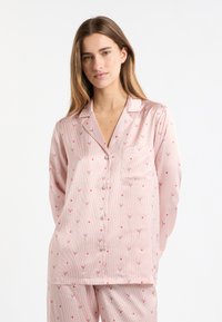 Conjunto de pijama rosa claro con rayas verticales y pequeños patrones florales. Cuenta con cuello, cierre de botones en la parte delantera y un bolsillo único en el pecho. Tela suave.