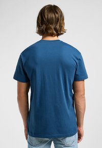 Mörkblå bomullströja med korta ärmar och rund halsringning, som visar en jämn och slät textur från bakåtsidan.