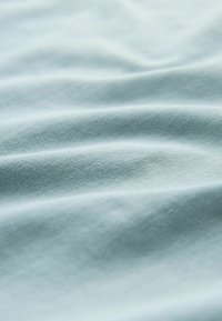 Hellblauer Stoff mit glatter Textur, versehen mit dezenten Falten und einem weichen, gleichmäßigen Webmuster. Geeignet für Bekleidung oder Polsterung.