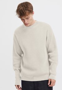 Hellbeige Waffelstrick-Pullover mit langen Ärmeln, gerippten Bündchen und rundem Ausschnitt. Weiche Textur, lockere Passform, minimalistischem Design.