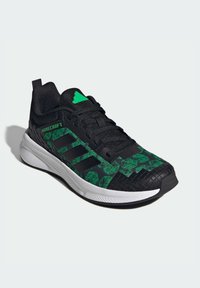 Czarny sneaker z zielonym pikselowanym wzorem, lekką siateczkową cholewką, teksturowaną gumową podeszwą i trzema czarnymi paskami Adidas.