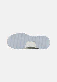 Semelle de chaussure en caoutchouc gris clair avec un motif texturé et strié pour une meilleure adhérence. Logo visible sur le côté près du talon.