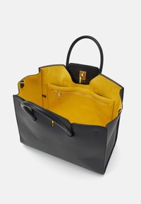 Černá kožená taška s žlutým semišovým interiérem, vybavená dvěma madly, kapsou na zip a bezpečným uzávěrem.