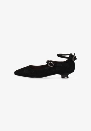 Scarpa bassa in suede nero con tacco basso, punta appuntita, cinturino alla caviglia e fibbia laterale su sfondo bianco.