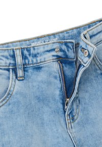Jeans de mezclilla azul claro con una cremallera estándar, costuras visibles y una etiqueta de "República del Mezclilla" en la cinturilla.