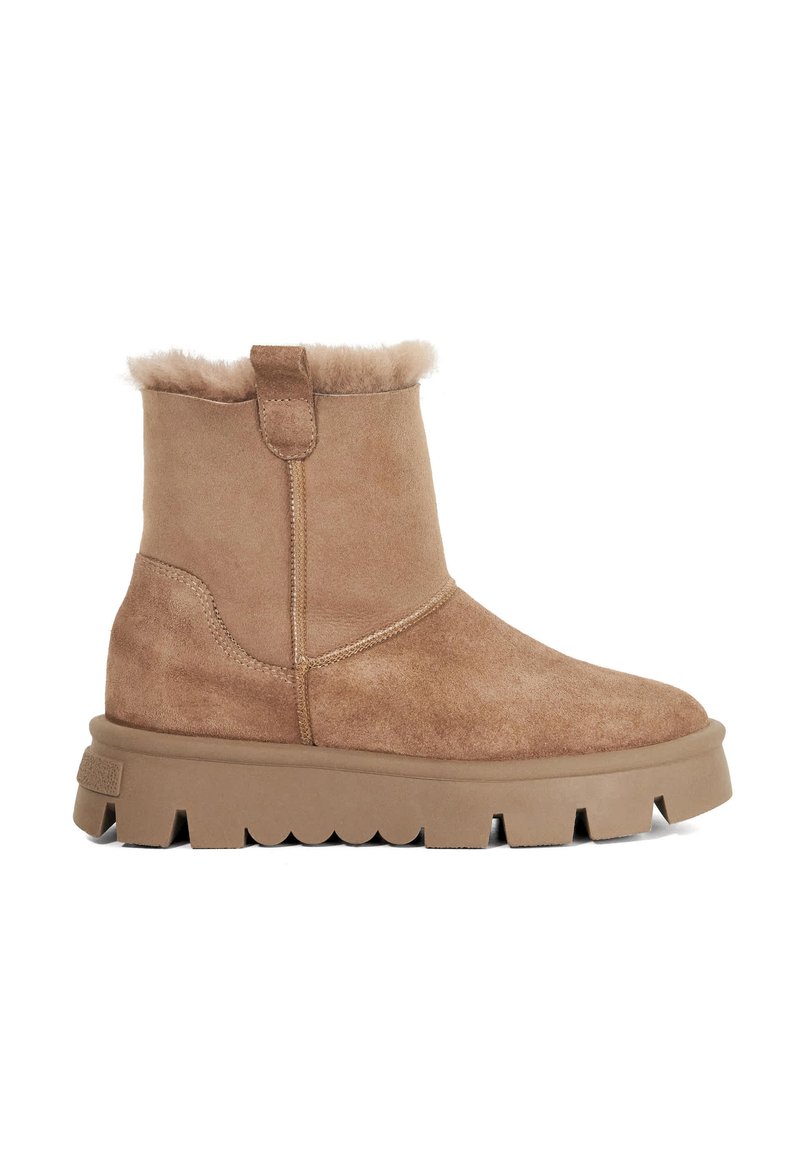 Tan suede ankle boots with a shearling lining, rounded toe, and a thick, textured rubber sole featuring scalloped edges.
