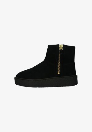 Bottines noires en daim avec une semelle extérieure noire texturée, dotées d'une fermeture éclair dorée sur le côté et d'éléments de design minimalistes.