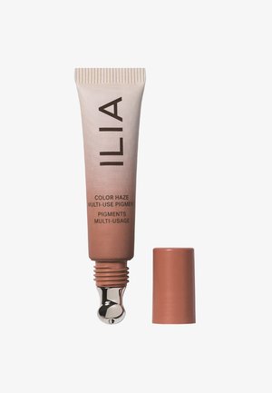 Crèmekleurige tube met een metalen applicatorpunt. Het etiket leest "ILIA Color Haze Multi-Use Pigment" in donkergrote tekst. De dop is solid beige.