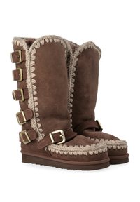 Stivali in suede marrone con un design alto, caratterizzati da cuciture decorative e sei fibbie laterali. Fodera morbida e suola in gomma piatta.