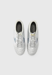 Chaussures de sport blanches avec une tige en cuir texturé, accents bleus, languette rembourrée et lacets gris. Dotées d'une semelle intérieure rembourrée pour plus de confort.