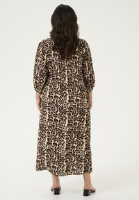 Vestido maxi de estampado de leopardo en beige y negro con mangas abullonadas, cintura elástica y dobladillo fluido. Tejido suave con un ligero brillo.