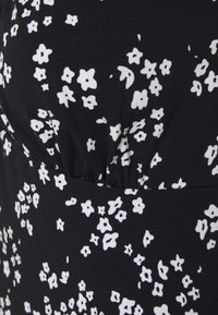 Musta kangas, jossa on hajallaan pieniä valkoisia kukkakuoseja ja näkyviä saumoja sekä kevyitä rypytyksiä.