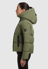 Giacca imbottita verde oliva, con cappuccio, tasche con zip e design trapuntato. Realizzata in un materiale liscio e leggero.