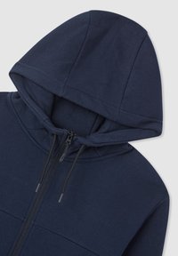 Felpa con zip di colore blu navy, con un cappuccio foderato, dettagli in tessuto a contrasto sul petto e due cordini regolabili. Texture morbida.