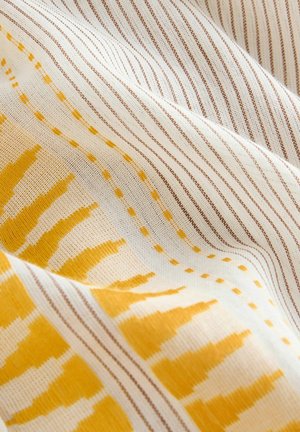 Baumwollstoff mit einem cremigen Hintergrund, der gelbe und braune Streifenmuster sowie abstrakte gelbe designs zeigt, wobei Textur und Webart hervorgehoben werden.