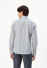 Lange mouwen shirt in lichtblauw met een geometrisch patroon. Heeft een gespreide kraag, knoopmanchetten en een licht gebogen zoom.