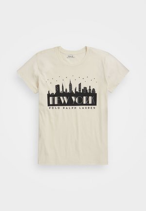 Beige T-shirt met zwarte afbeelding van de skyline van New York, sterren erboven, en de tekst "NEW YORK POLO RALPH LAUREN" op het midden van de voorkant.