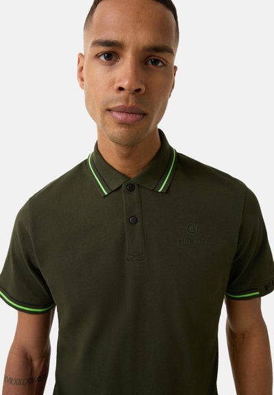 Olive green polo shirt with black buttons, black and neon green striped collar, and logo detail on the chest. Textured cotton fabric.