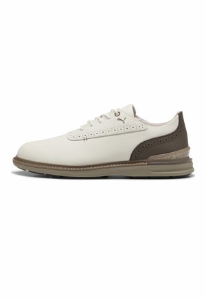 Witte vetersneaker met een bruine geperforeerde hiel, beige zool en een klein Puma-logo aan de zijkant, gezien van het linkerprofiel.