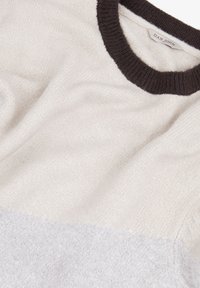 Maglione lavorato a maglia color crema con un colletto a girocollo a coste di un marrone scuro. La texture è morbida con un leggero gradiente che va da tonalità chiare a tonalità più scure.