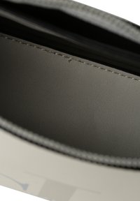 Detailní záběr na světle šedou podšívku a švy uvnitř béžové kožené boty.