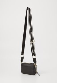 Borsa a tracolla nera in pelle sintetica con forma rettangolare. Presenta una superficie testurizzata, accessori dorati e una tracolla in contrasto bianco e nero.