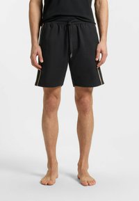 Zwarte katoenen shorts met een elastische tailleband en trekkoord. Kenmerkt zijsstrips in een lichtere kleur. Tot slot, knielange stijl.