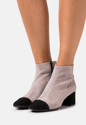 Bottines en daim gris clair avec embout noir et talon bloc. Dotées d'une fermeture éclair à l'arrière et d'une texture lisse.