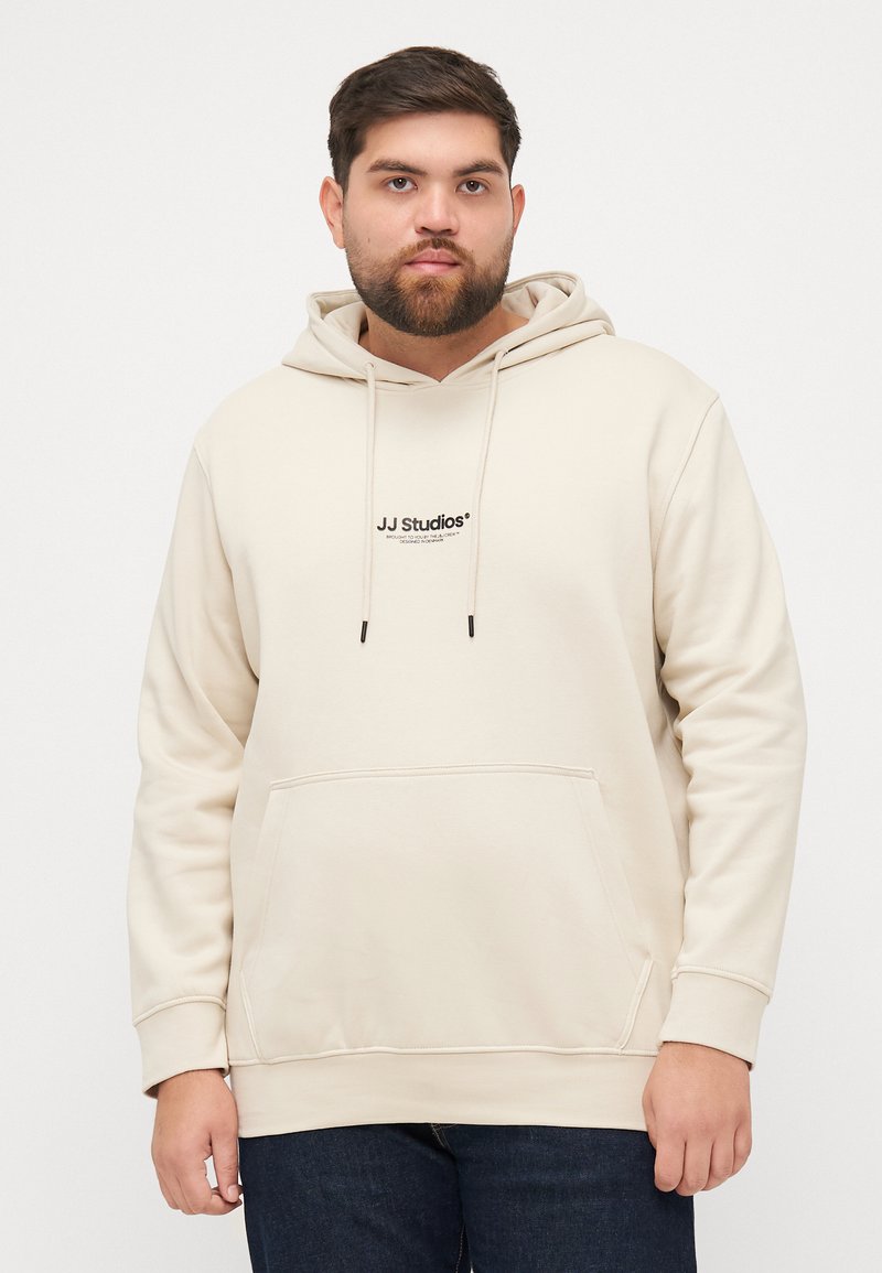 Beige Kapuzenpullover mit einer Fronttasche, Kapuze mit Kordelzug und schwarzem "JJ Studios"-Logo auf der Brust. Weicher Stoff, lässige Passform, gerippte Bündchen.