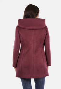 Cappotto borgogna con un ampio colletto pieghettato, texture liscia, maniche lunghe e silhouette sartoriale, esposto da dietro.