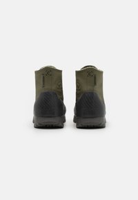 Vodotěsné olivově zelené boty Converse All Star s texturovanou černou podrážkou, s logem na patě a vysokým střihem.