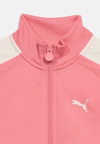 Ροζ μπουφάν με φερμουάρ, ριμπ λαιμόκοψη, λευκές πλαϊνές πινελιές και μικρό λευκό λογότυπο Puma στο δεξί στήθος.