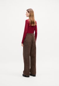 Long-sleeve red ribbed top paired with high-waisted brown corduroy wide-leg pants. Black chunky sole shoes complete the outfit.