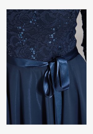 Granatowa sukienka z koronkową górą ozdobioną cekinami, satynowym paskiem w talii i gładką, zwiewną spódnicą. Miękka tekstura i elegancki fason.