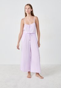 Lila jumpsuit met verstelbare bandjes, een taille met trekkoord, brede pijpen en een lichte, gestructureerde stof. Minimalistisch ontwerp, zonder patronen.