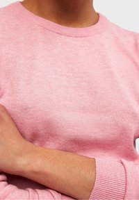 Rosa stickad tröja med rund hals och ribbade ärmar, med en mjuk textur och en kroppsnära design.