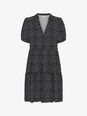 Melnas, ar īsām piedurknēm kleita ar dziļu V-veida izgriezumu un vairākpakāpju svārkiem, pārklāta ar mazām baltām punktiņām, kas vienmērīgi izkliedētas visā audumā.