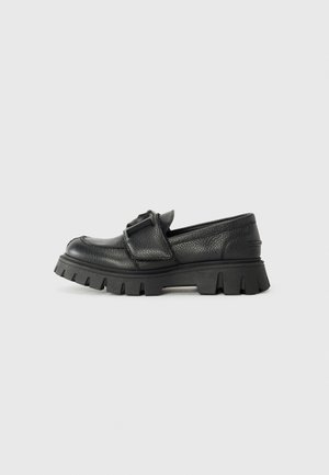 Čierne kožené slip-on topánky s textúrovaným povrchom a masívnou gumovou podrážkou s hlbokými drážkami. Odtieň s nastaviteľnou sponou.