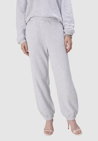 Helle graue Jogginghose aus weichem Baumwollmix, mit elastischem Bund und gerafften Bündchen an den Knöcheln. Glatte Textur, lockere Passform.