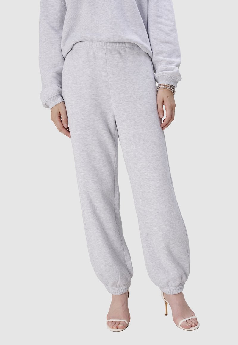 Helle graue Jogginghose aus weichem Baumwollmix, mit elastischem Bund und gerafften Bündchen an den Knöcheln. Glatte Textur, lockere Passform.