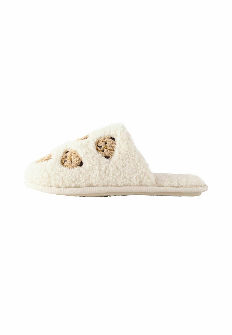 Fuzzy white slippers with beige cookie-shaped accents on the upper. Soft texture with a flat sole and open back design.