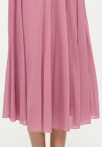 Ροζ midi φόρεμα από ελαφρύ, διαφανές ύφασμα. Διαθέτει ρέον, πλισέ σχέδιο με απαλή υφή και ήπιο πέσιμο στο τελείωμα.