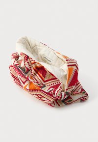 Textilné púzdro s prešívaným bielym vnútrom, zdobené živým geometrickým vzorom v červenej, oranžovej a béžovej farbe. Zaoblený tvar s viazanými detailmi.