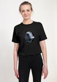 Svart T-shirt med ett grafiskt tryck av Dödsstjärnan i grått och vitt, omgiven av en stjärnspäckad bakgrund, tillverkad av bomullsmaterial.